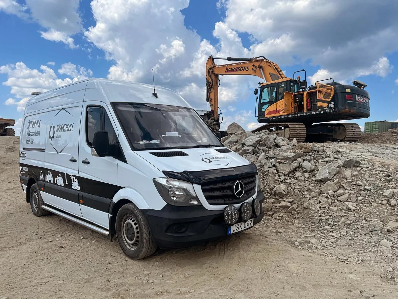 Vit servicebil från Maskinservice i Göteborg parkerad vid byggarbetsplats med grävmaskin i bakgrunden